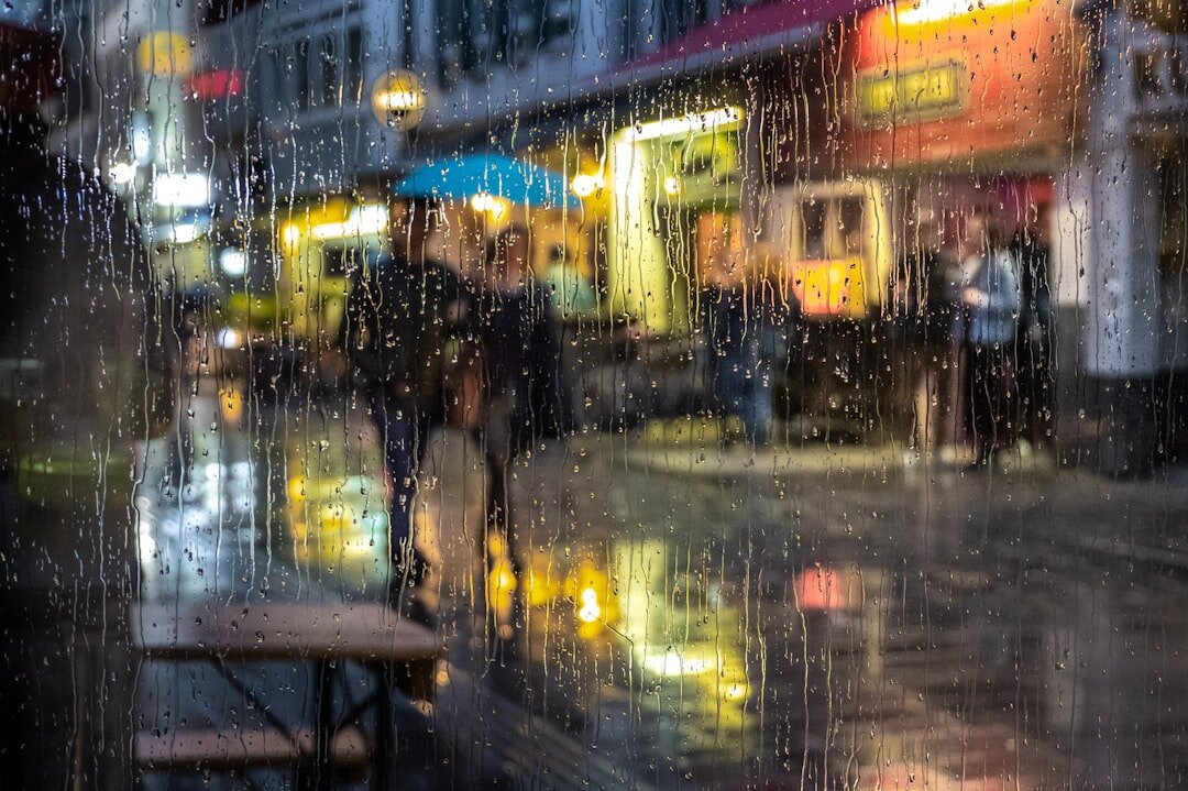 Chilean person walking down a rainy street holding an umbrella
